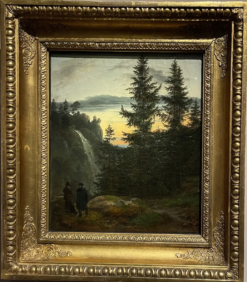 Two men watching a waterfall in the mountains.