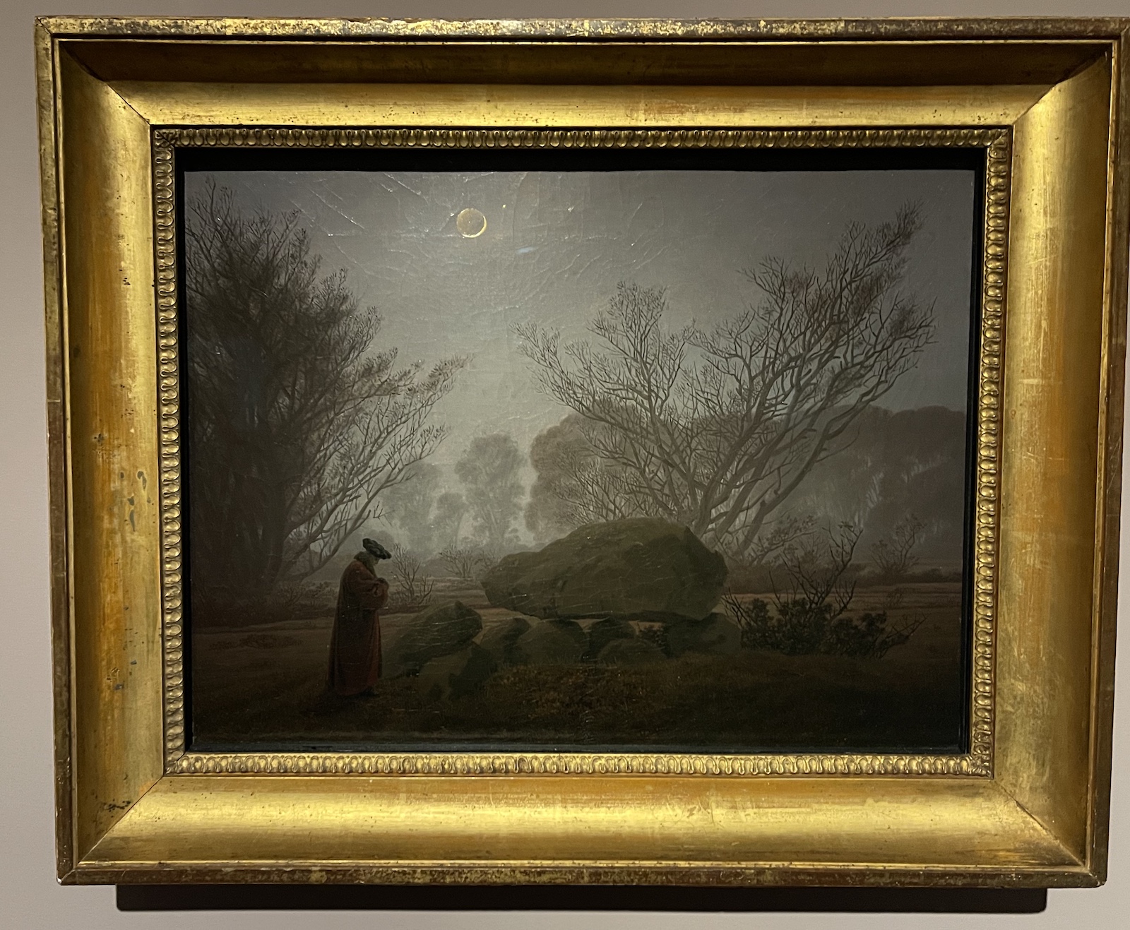 Late evening lit by a small waxing moon, a man standing next to a prehistoric dolmen